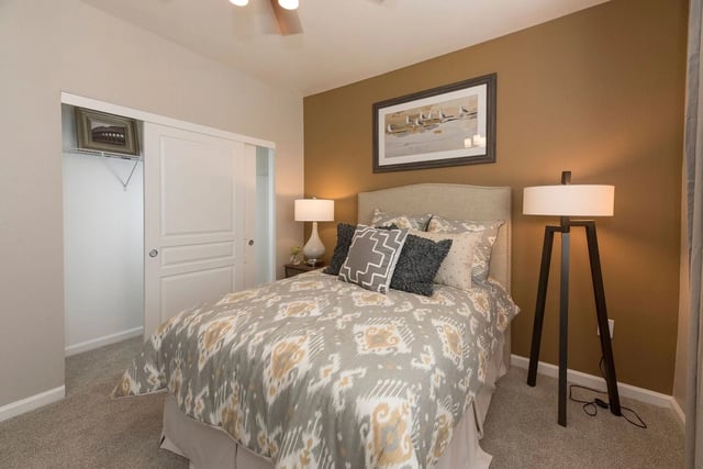 Bedroom with a queen-size bed, sliding closet door, and artwork.