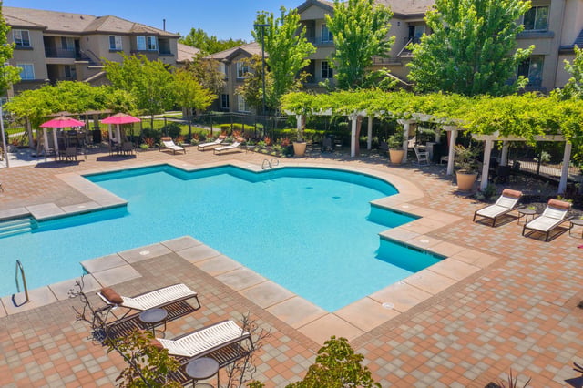 Resort-style swimming pool with lounge chairs and umbrellas.