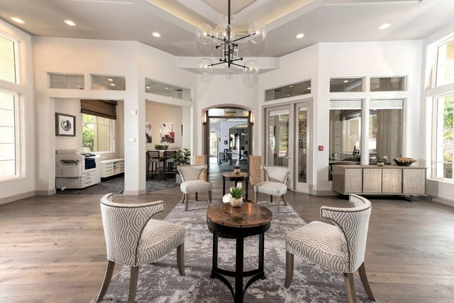 Cozy seating area with chairs and tables in a multifamily property lounge.