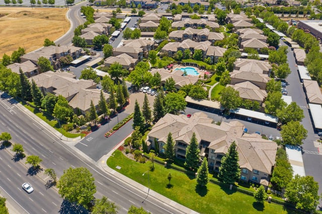 Aerial view of apartment buildings with a swimming pool and lush landscaping.