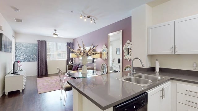 Modern kitchen and living area with purple accent wall and stylish furniture.