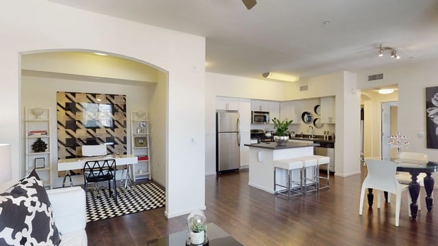 Modern apartment living area with a desk and kitchen island.
