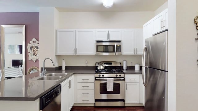 Modern kitchen with stainless steel appliances and white cabinets.