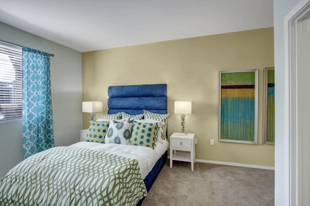 Bedroom with a large bed, blue headboard, and decorative pillows.