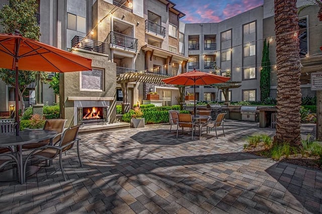 Outdoor living space with a fireplace, grills, and seating areas.