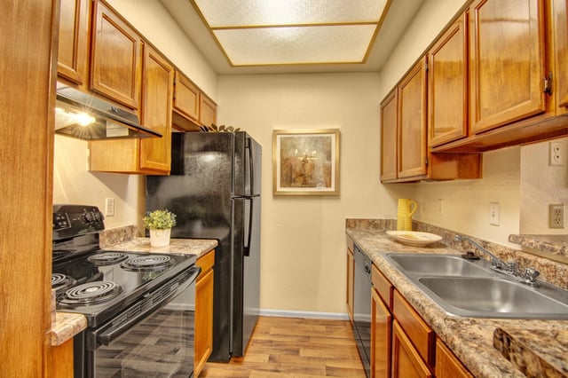 Kitchen with wood cabinets, black appliances, and granite countertops.