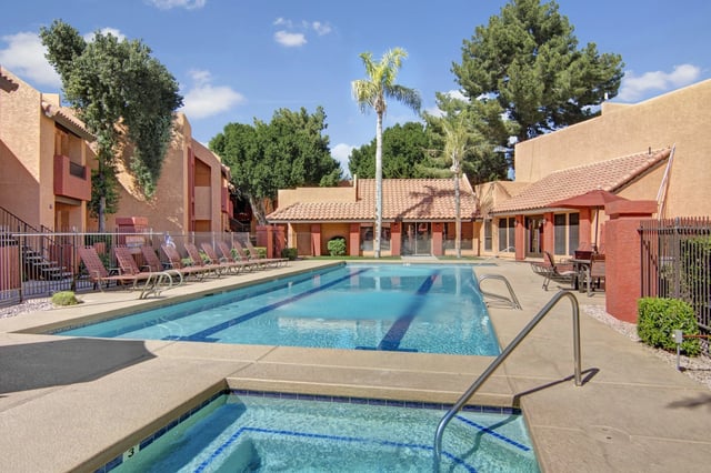 Outdoor swimming pool with lounge chairs and palm trees.