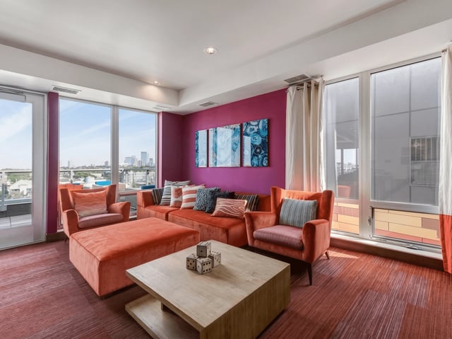 Stylish communal lounge with orange seating and city views.