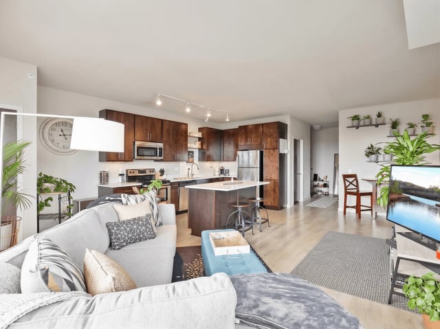 Modern living room and kitchen area with comfortable sofa, large TV, and island.