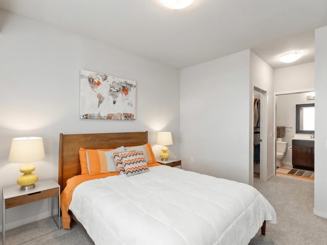 Bedroom with a queen-sized bed, nightstands, and a view into the bathroom and closet.