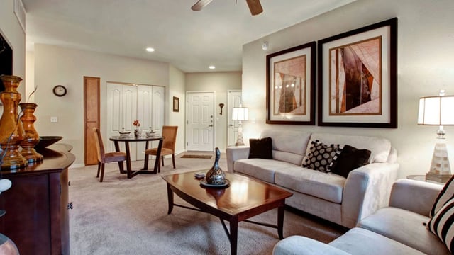 Living room with a sofa, coffee table, dining table, and artwork.