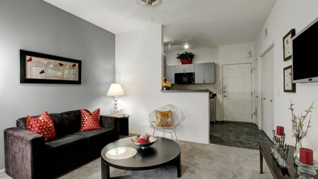 Modern living room with dark sofa, accent chairs, coffee table, and view of kitchen.