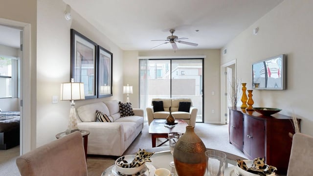 A well-decorated living room with a sectional sofa, coffee table, and a TV mounted on the wall.