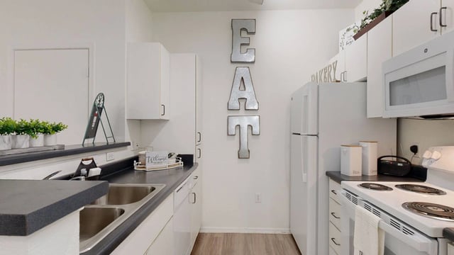 Modern kitchen with stainless steel appliances and white cabinetry.