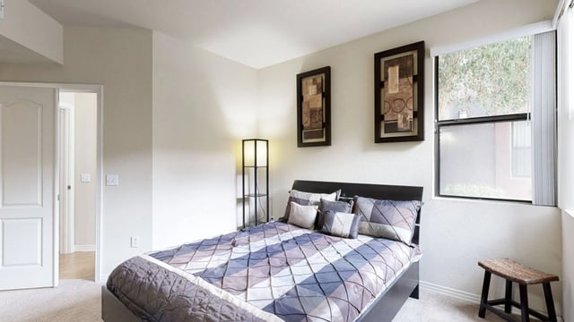 Bedroom with a queen-size bed, artwork, and a window.