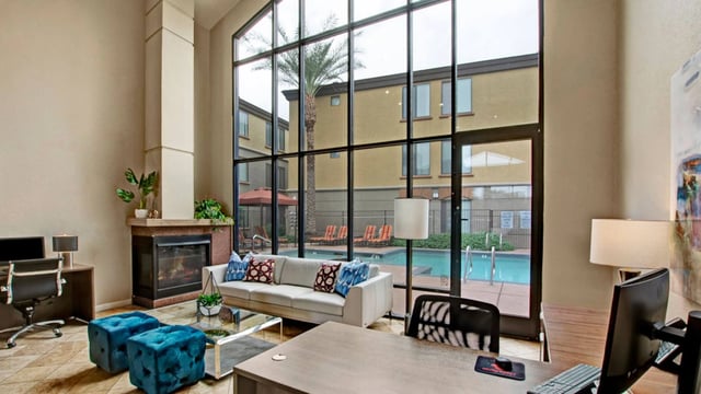 Lobby area with seating, fireplace, and view of the pool and lounge chairs.