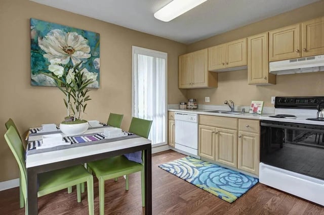 Kitchen and dining area with a table and chairs, cabinets, sink, dishwasher, and stove.