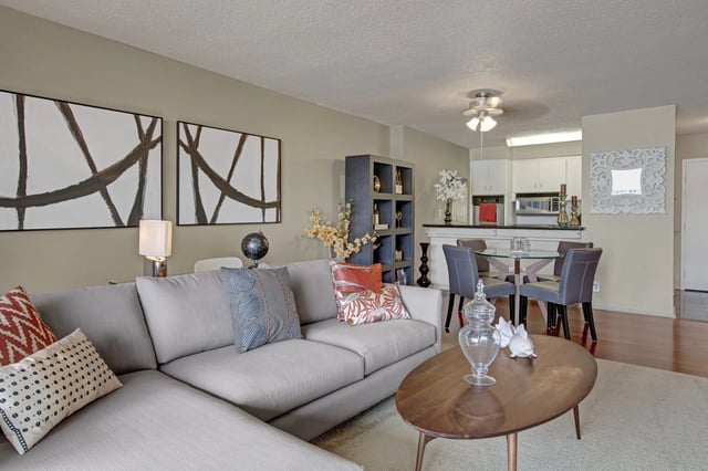 Modern living room and kitchen area with sectional sofa, dining table, and breakfast bar.