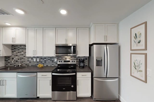 Modern kitchen with stainless steel appliances, white cabinets, and subway tile backsplash.