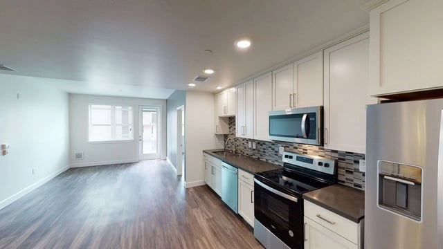 Modern kitchen with white cabinets, stainless steel appliances, and dark countertops.