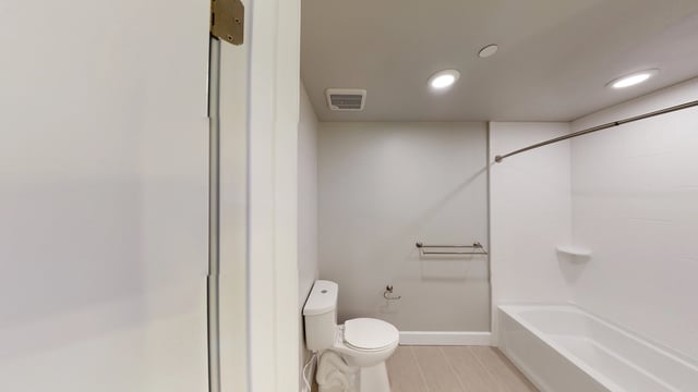 Clean and modern bathroom with toilet and bathtub.