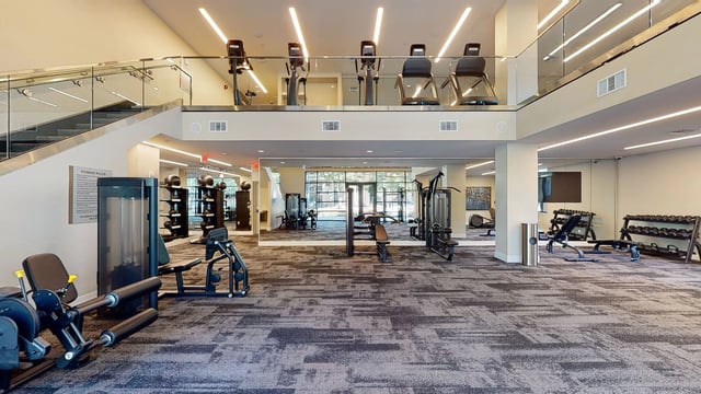 Two-story gym with cardio machines on the upper level and weight training equipment on the lower level.