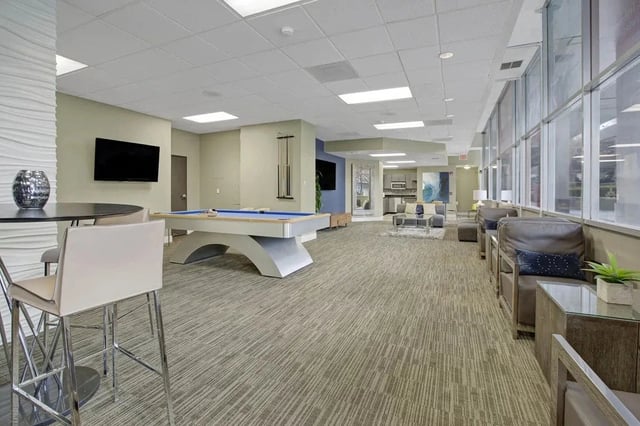 Community lounge area with a pool table, seating, and a kitchenette.