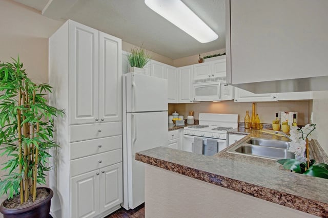 Modern kitchen with white cabinetry, stainless steel appliances, and granite countertops.