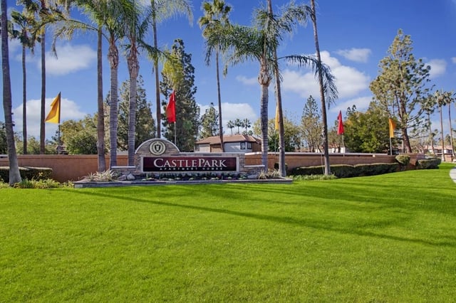 Castle Park Apartment Homes monument sign surrounded by palm trees and manicured lawns.