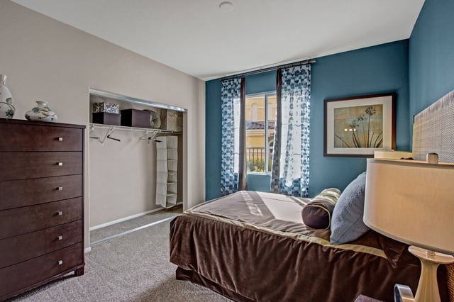 Bedroom with a queen-size bed, dresser, and closet.