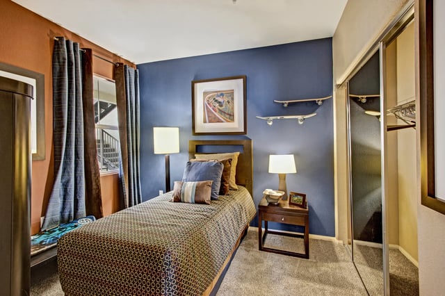 Bedroom with a twin bed, blue walls, and skateboards as decor.