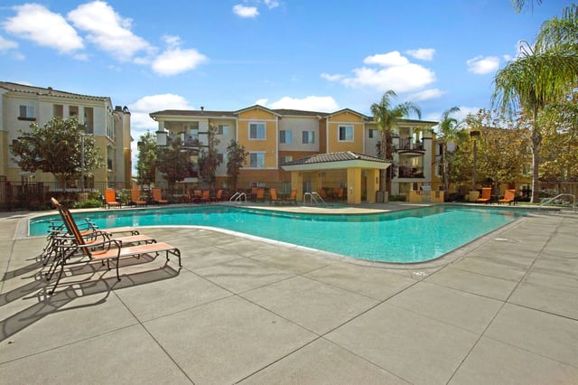 Resort-style swimming pool with lounge chairs and cabana at apartment complex.
