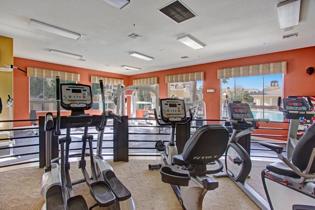 Gym with cardio machines and a view of the pool.