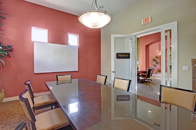 Conference room with large table and chairs, whiteboard, and exit sign.