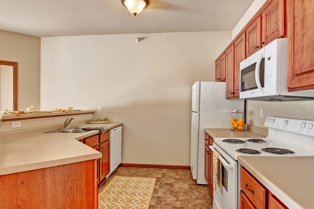 Kitchen with wooden cabinets, white appliances, and a sink.