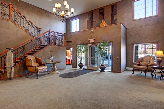 Elegant building lobby with a grand staircase, comfortable seating, and large windows.