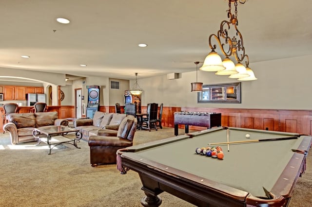 Community lounge with pool table, foosball, dartboard, seating, and bar area.