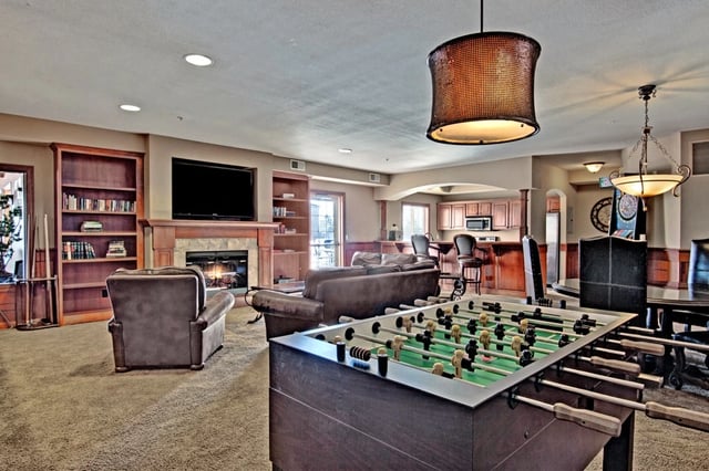 Community game room with foosball table, fireplace, lounge seating, and wet bar.