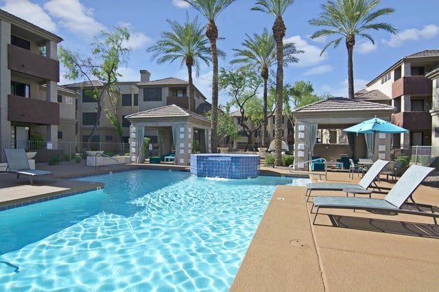 Resort-style swimming pool with lounge chairs and cabanas