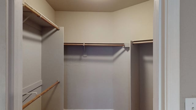 Empty walk-in closet with wooden closet rods and shelves.