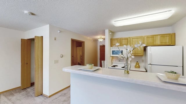 Kitchen counter with white cabinets, refrigerator, and stove. Open doorway leads to a closet.