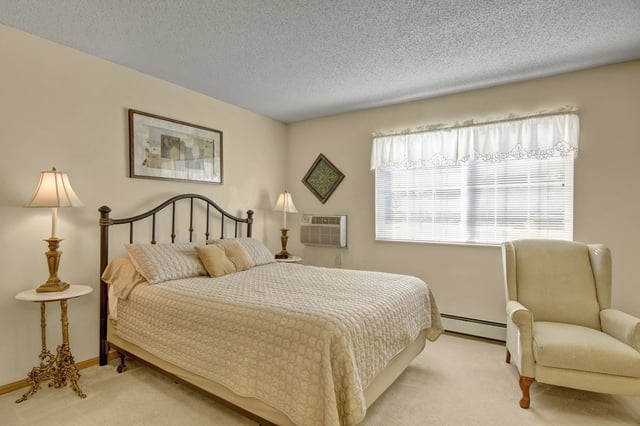 Bedroom with a queen-sized bed, nightstand, chair, and window.