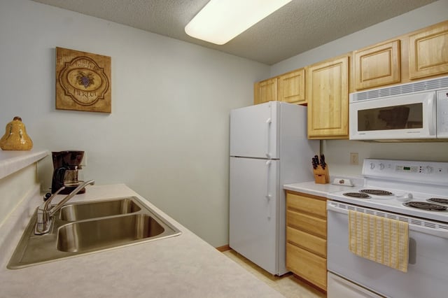 Kitchen with white appliances, including refrigerator, microwave, and stove, plus a double sink.