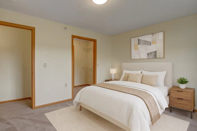 Bedroom with a queen-size bed, nightstand, closet, and artwork.