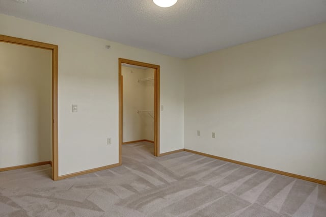 Empty bedroom with a closet and neutral carpet.