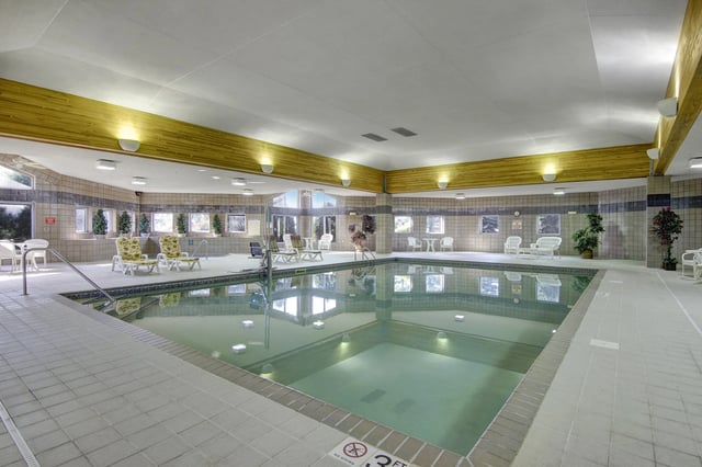 Indoor swimming pool with lounge chairs and tables.