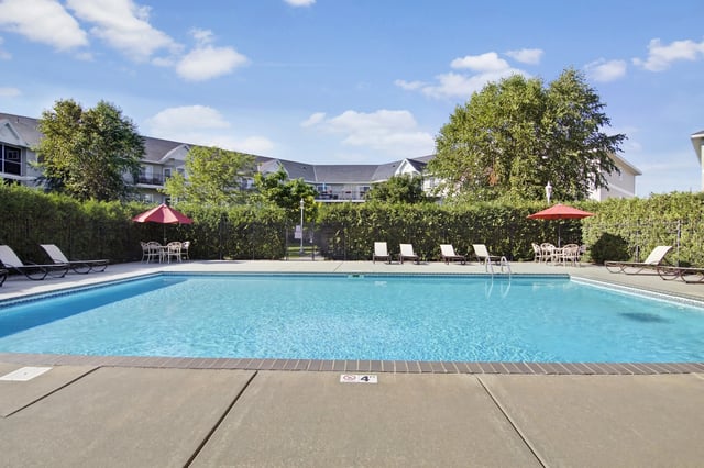 Outdoor swimming pool with lounge chairs and umbrellas.