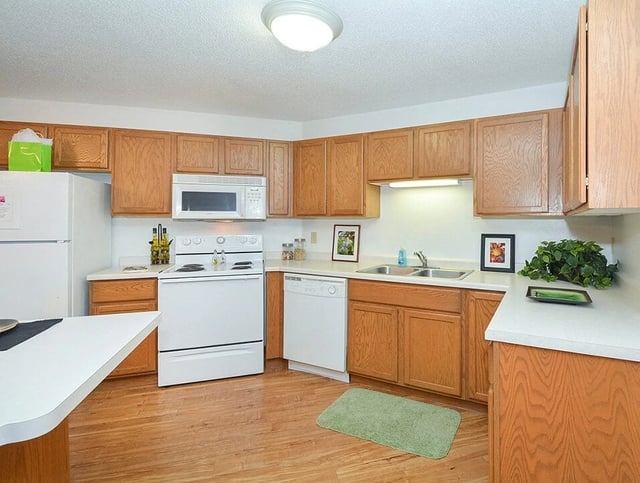 Kitchen with oak cabinets, white appliances, and hardwood floors.