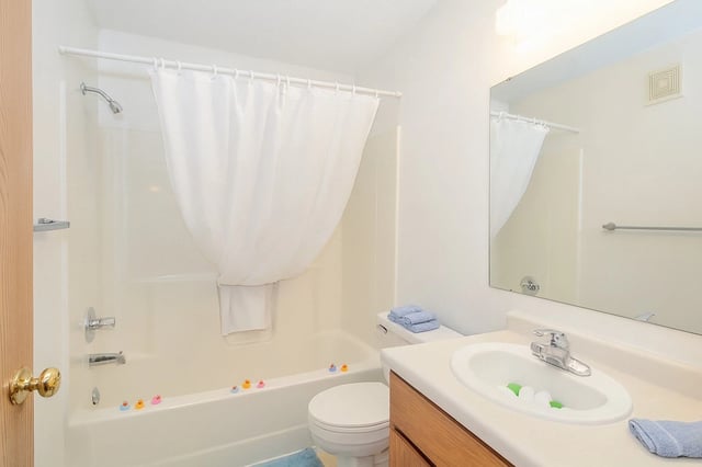 Clean bathroom with a bathtub, toilet, and vanity sink.