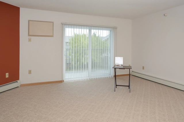 Empty living room with sliding glass doors and a small table.